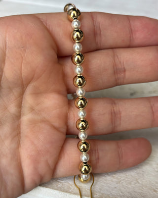 Gold and white beaded bracelet on a hand