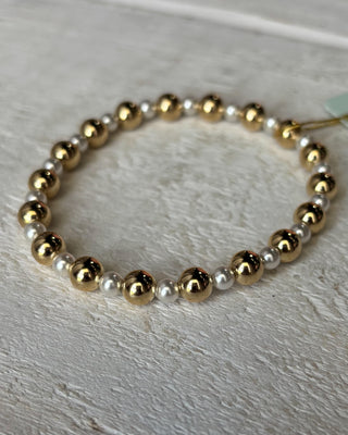 Bracelet with gold and silver beads on a light wooden surface