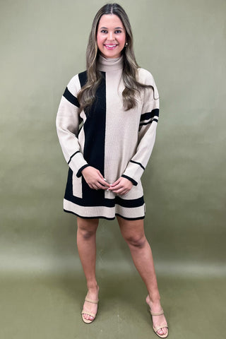 Woman wearing a beige and black dress against a plain background