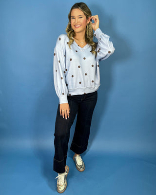 Light blue textured polka dot V-neck top with contrasting brown dots, relaxed drop shoulders, long sleeves