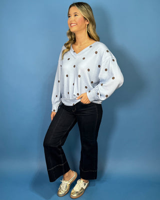 Light blue textured polka dot V-neck top with contrasting brown dots, relaxed drop shoulders, long sleeves