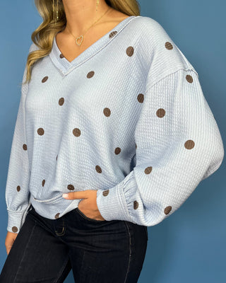 Light blue textured polka dot V-neck top with contrasting brown dots, relaxed drop shoulders, long sleeves