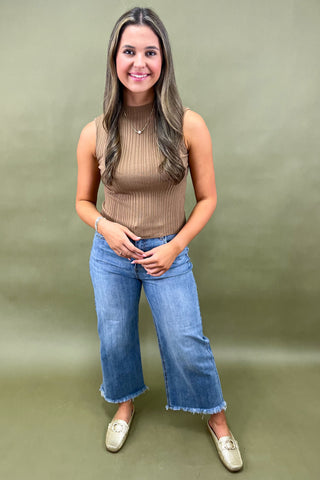 Camel ribbed sleeveless mock neck top styled with light wash wide leg frayed hem jeans and gold loafers