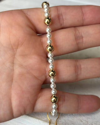 Bracelet with alternating gold and pearl beads on a hand