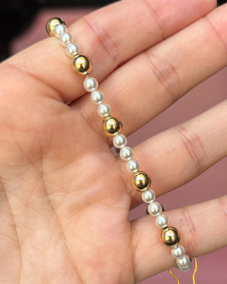 Gold and pearl beaded bracelet on a hand with a blurred background