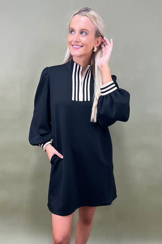 Woman wearing a black dress with white stripes on a plain background