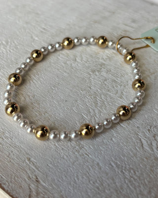 Bracelet with gold and white beads on a light surface