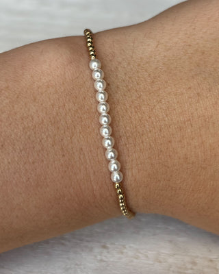Pearl bracelet on a wrist with a neutral background