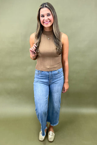 Camel ribbed sleeveless mock neck top styled with light wash wide leg frayed hem jeans and gold loafers