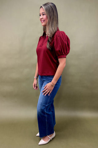 Woman wearing a red blouse and blue jeans against a green background
