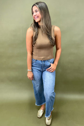 Camel ribbed sleeveless mock neck top styled with light wash wide leg frayed hem jeans and gold loafers