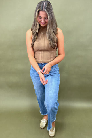 Camel ribbed sleeveless mock neck top styled with light wash wide leg frayed hem jeans and gold loafers