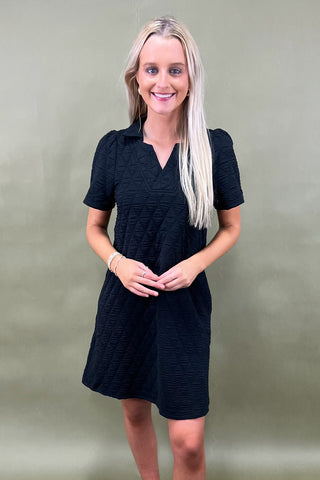Woman wearing a black dress against a plain background