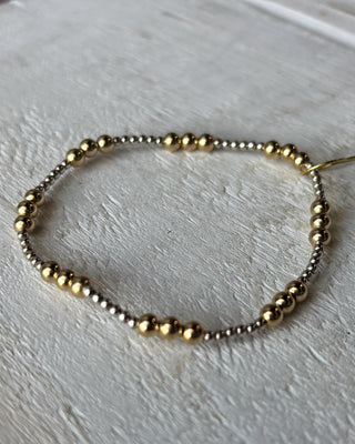Bracelet with gold and silver beads on a light wooden surface