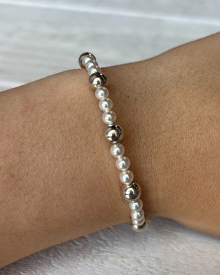 Pearl bracelet on a wrist with a neutral background