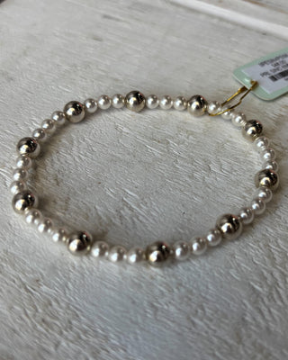 Pearl necklace on a light wooden surface with a price tag attached.