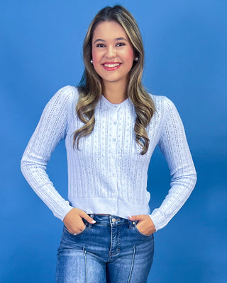 wearing a light blue long-sleeve button-front knit top and blue jeans.