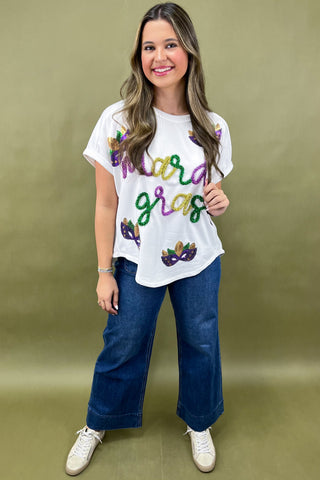 Woman wearing a white t-shirt with colorful text and blue jeans on a green background