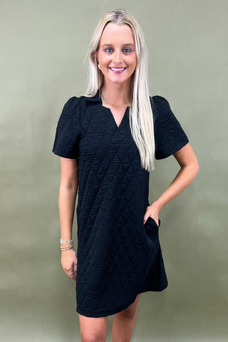 Woman wearing a black dress against a green background