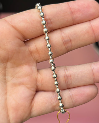 Silver beaded bracelet on a hand with a blurred background