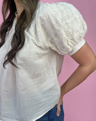White blouse with puff sleeves worn by a person on a pink background