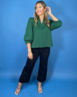 Emerald green scalloped blouse with a split neckline, puff sleeves, and scalloped trim for a polished feminine look.