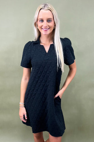 Woman wearing a black dress against a green background