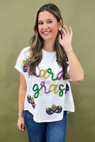 Woman wearing a white t-shirt with 'Mardi Gras' text and colorful beads on a green background