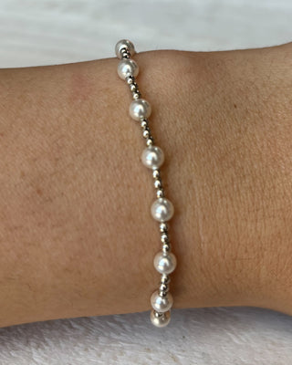 Pearl bracelet on a wrist with a plain background