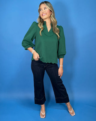 Emerald green scalloped blouse with a split neckline, puff sleeves, and scalloped trim for a polished feminine look.