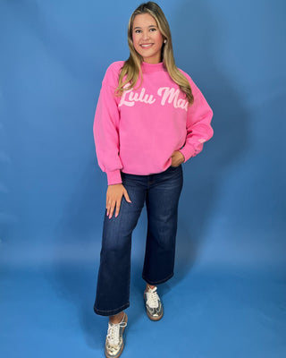 Pink LULU MAC graphic sweatshirt with long sleeves and crew neckline, styled with dark wash wide leg jeans.