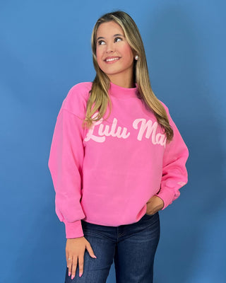 Pink LULU MAC graphic sweatshirt with long sleeves and crew neckline, styled with dark wash wide leg jeans.