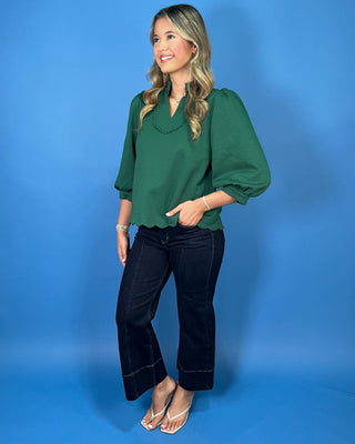 Emerald green scalloped blouse with a split neckline, puff sleeves, and scalloped trim for a polished feminine look.