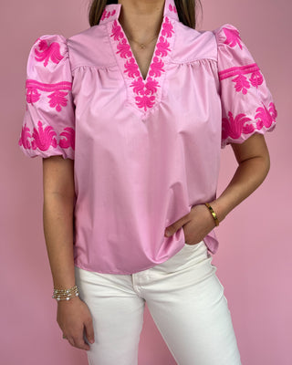 Pink blouse with floral embroidery on a pink background