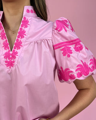 Pink blouse with floral embroidery on a pink background