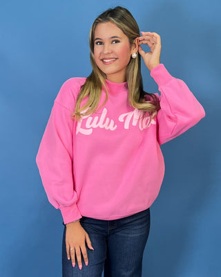Pink LULU MAC graphic sweatshirt with long sleeves and crew neckline, styled with dark wash wide leg jeans.