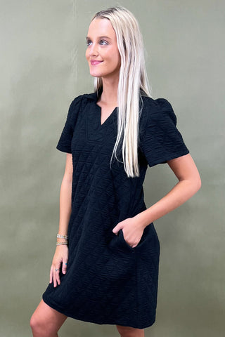 Woman wearing a black dress against a green background