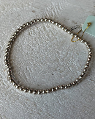 Silver beaded bracelet on a light wooden surface