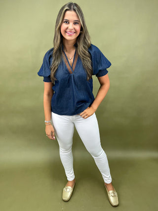 Cream and navy puff sleeve blouse with geometric print styled with light wash wide leg jeans and white sneakers.