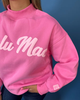 Pink LULU MAC graphic sweatshirt with long sleeves and crew neckline, styled with dark wash wide leg jeans.