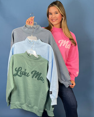 Pink LULU MAC graphic sweatshirt with long sleeves and crew neckline, styled with dark wash wide leg jeans.