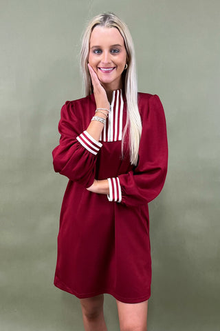 Woman wearing a burgundy outfit with white stripes on a green background