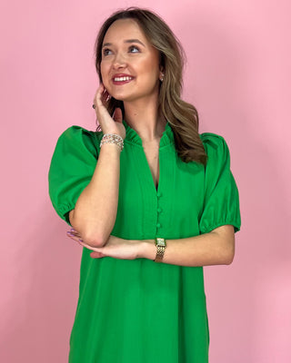 Woman wearing a green dress against a pink background