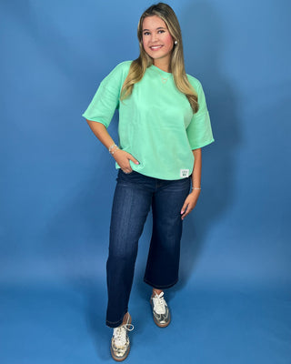 Mint green LULU MAC short sleeve top with a relaxed fit, styled with dark wash wide leg jeans.