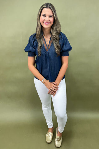 Cream and navy puff sleeve blouse with geometric print styled with light wash wide leg jeans and white sneakers.