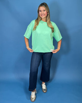 Mint green LULU MAC short sleeve top with a relaxed fit, styled with dark wash wide leg jeans.