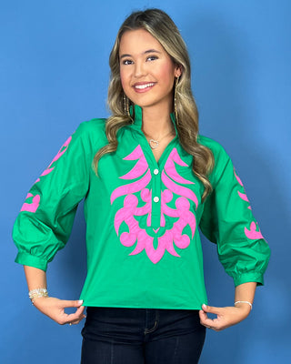 Green blouse with bright pink embroidered detailing, button neckline, and three-quarter puff sleeves.