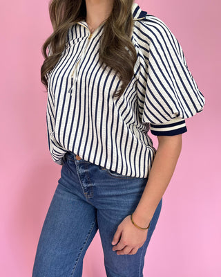 Person wearing a striped shirt and jeans against a pink background