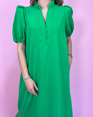 Green dress worn by a person against a pink background