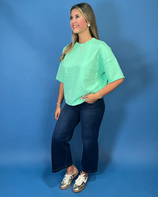 Mint green LULU MAC short sleeve top with a relaxed fit, styled with dark wash wide leg jeans.
